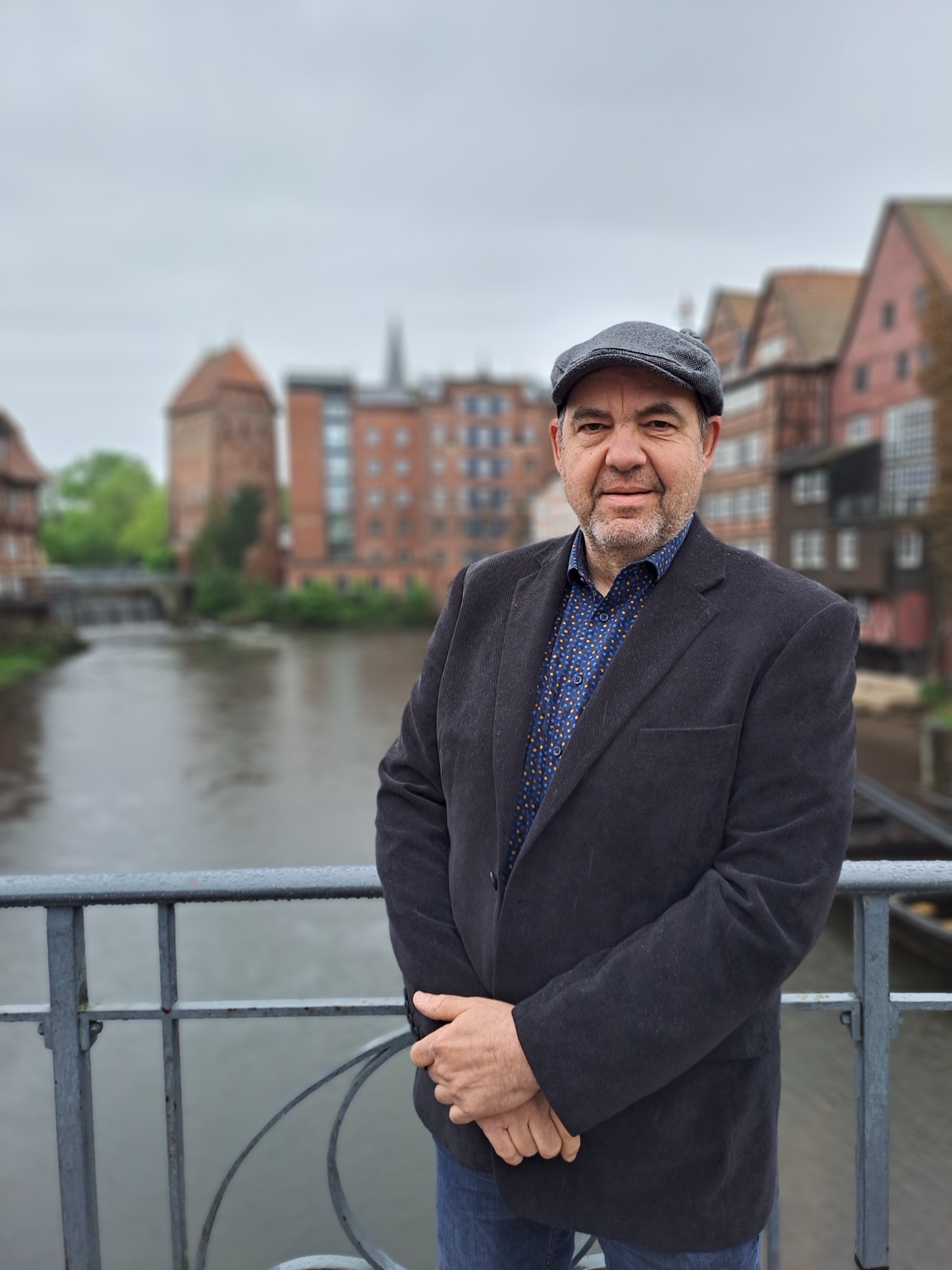 Arnd Hildebrandt steht auf einer Brücke vor einer historischen Stadtkulisse.